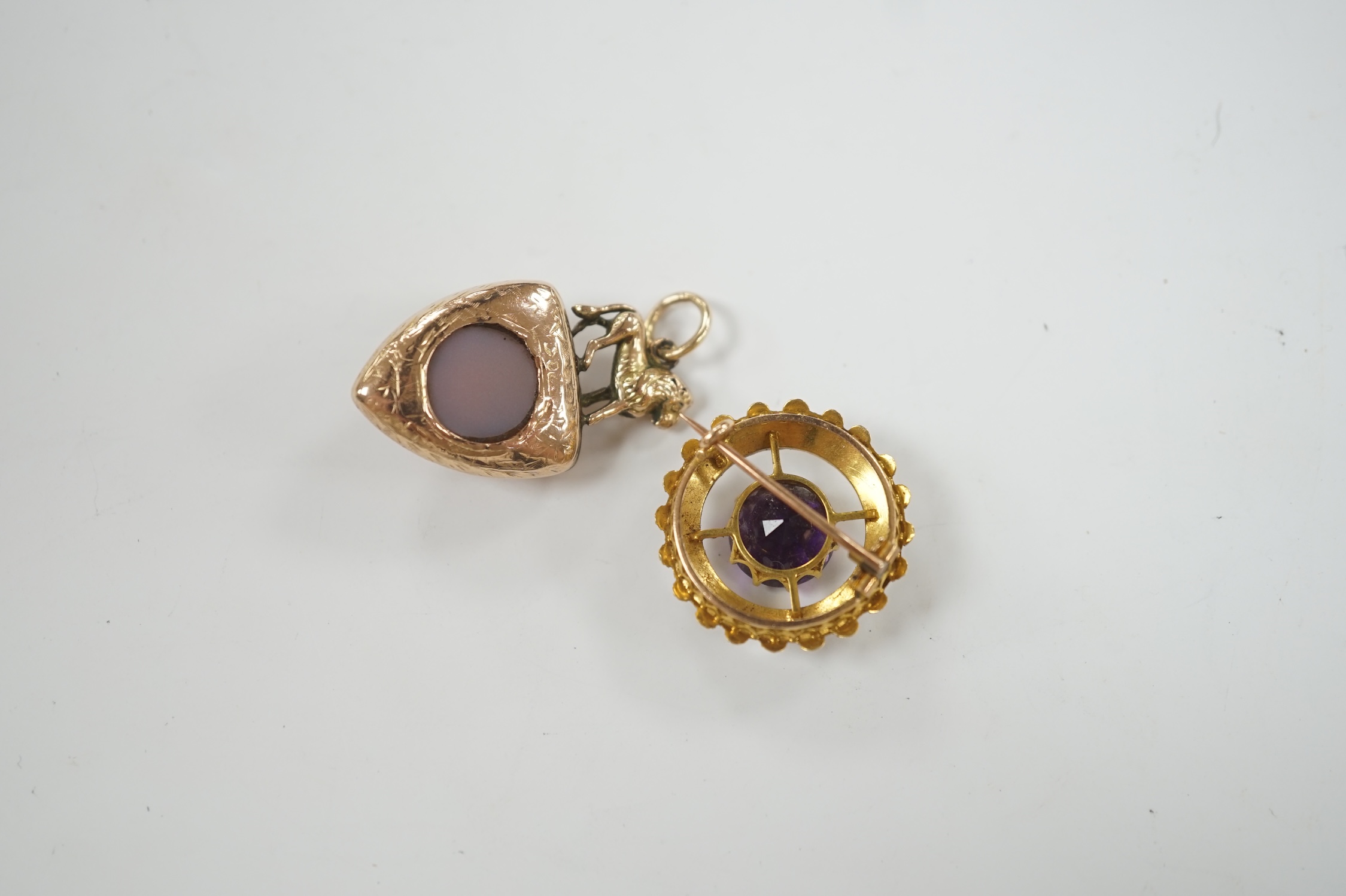 A Victorian yellow metal and two sided chalcedony set shield shaped pendant, with lion surmount, 31mm, together with an early 20th century yellow metal, amethyst and split pearl set circular brooch.